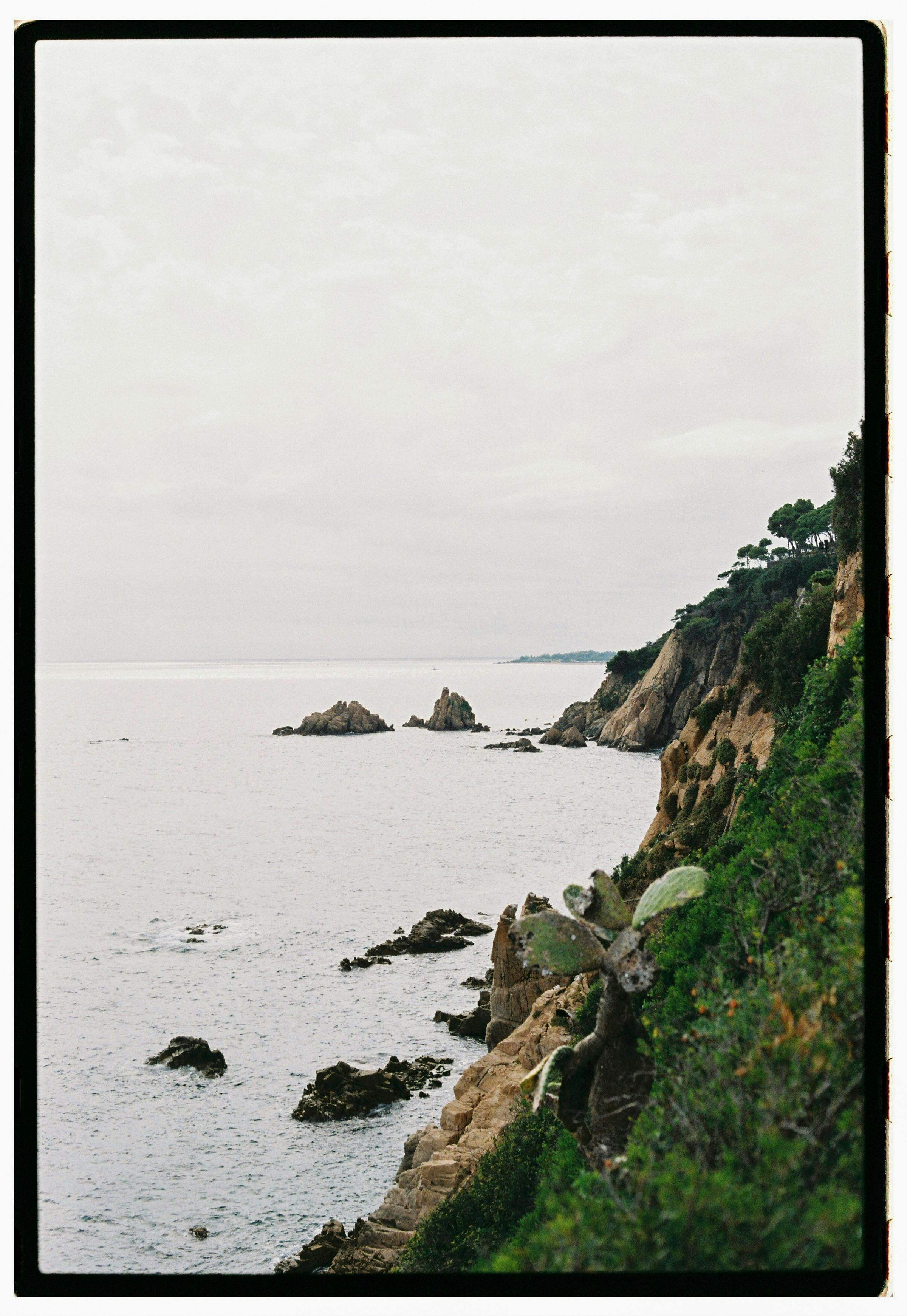Breathtaking view of rocky cliffs along the Mediterranean Sea under a cloudy sky.