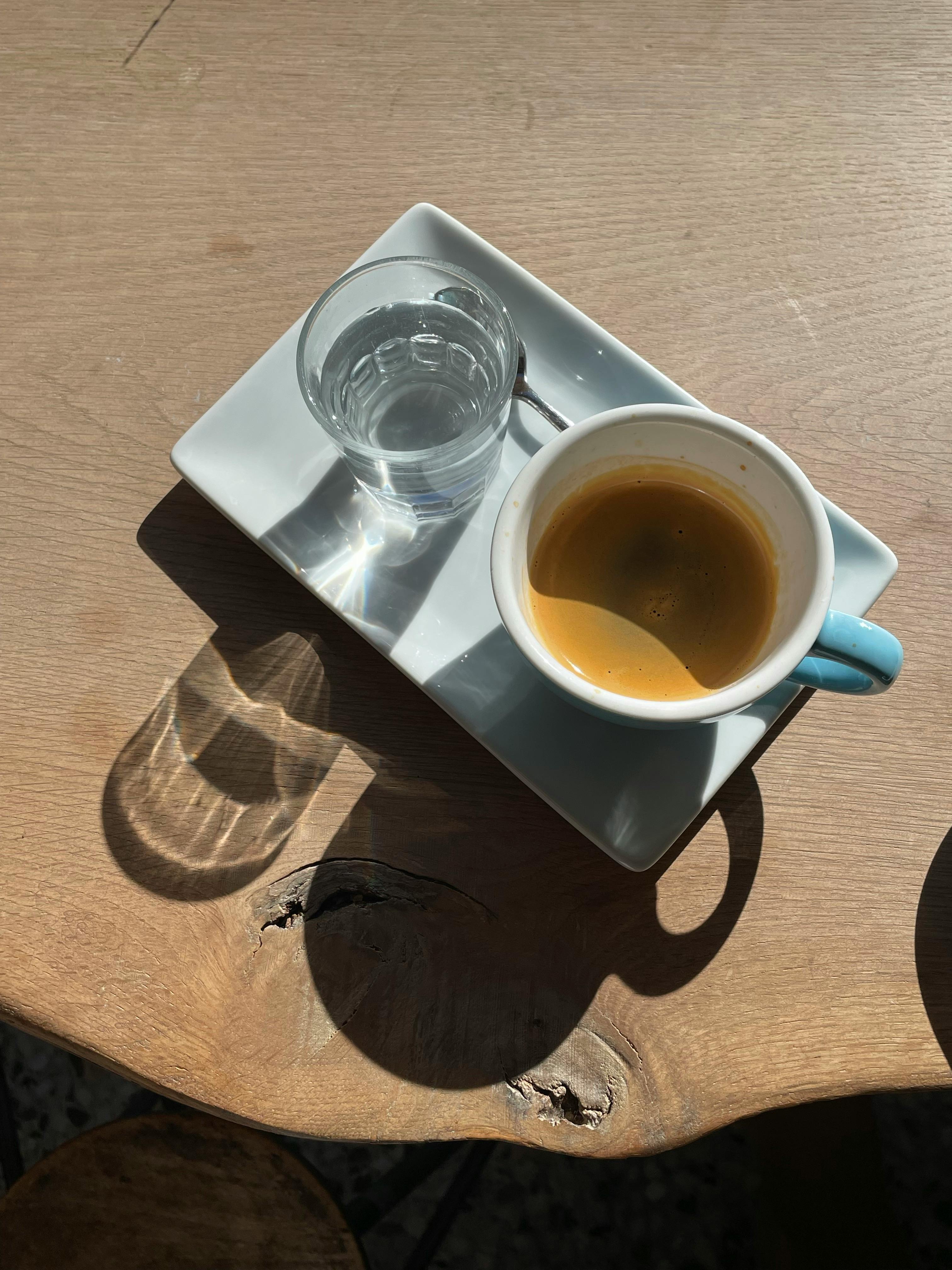 Top view of espresso and water on a sunlit table. Perfect for coffee enthusiasts.