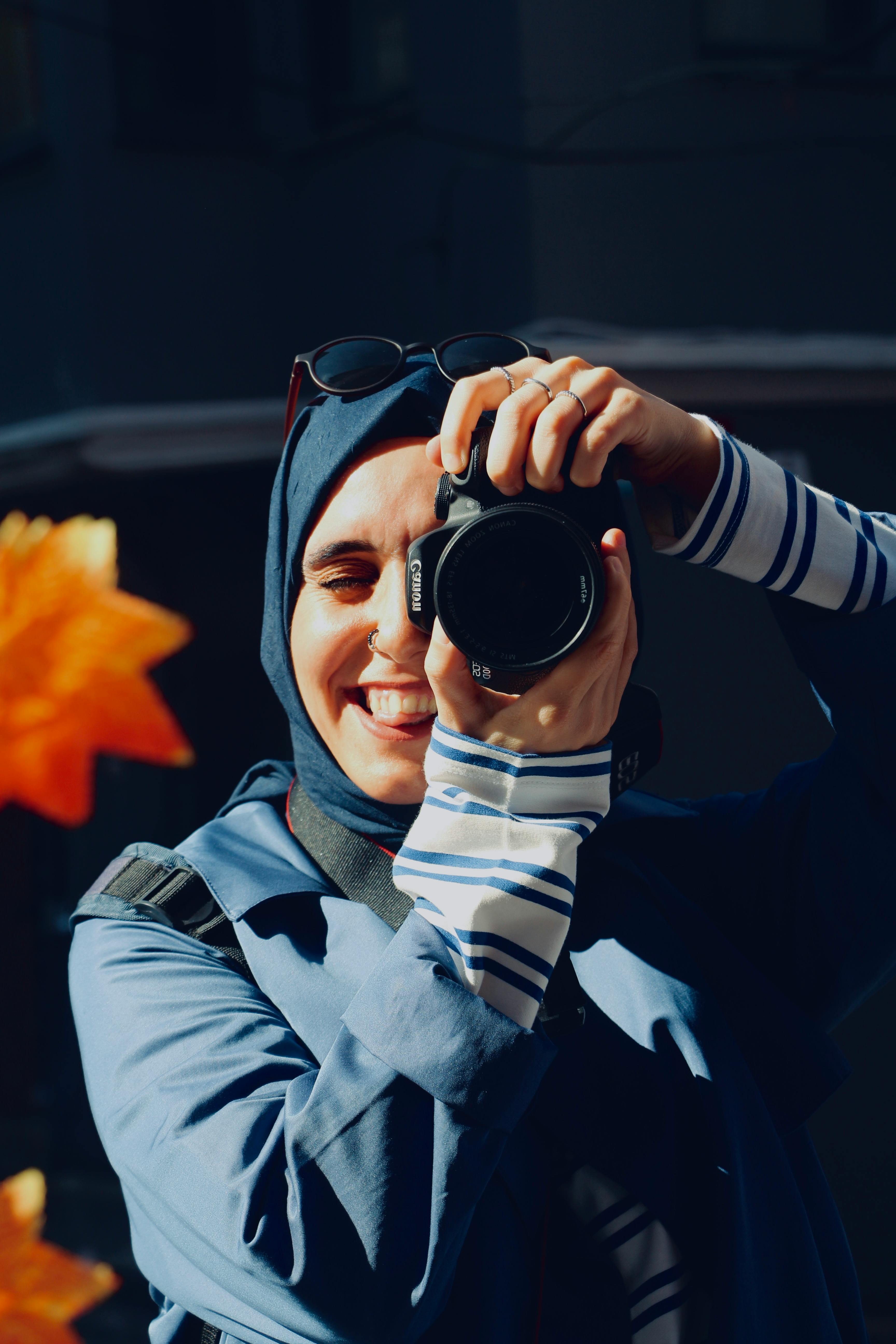 Female photographer enjoying a sunny outdoor photography session in stylish attire.