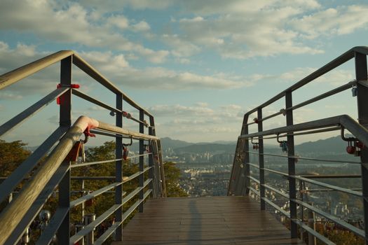 Love locks adorn a railing with a scenic view of Seoul, captured from a Namsan tower lookout.