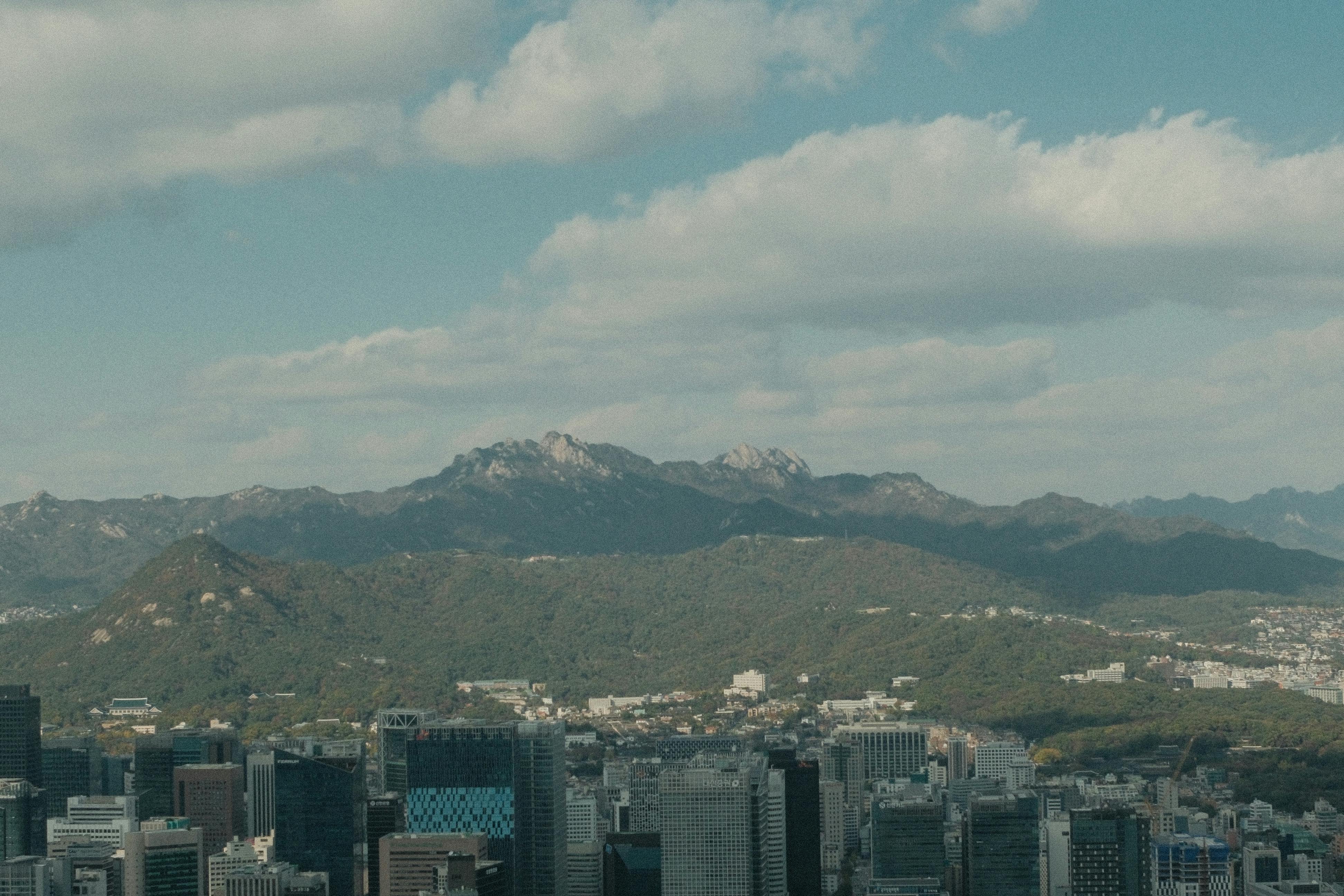 Panoramic view of Seoul's skyline with mountains and a majestic sky in the background.