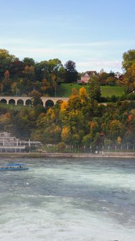 Picturesque autumn view of a river and viaduct surrounded by colorful trees.