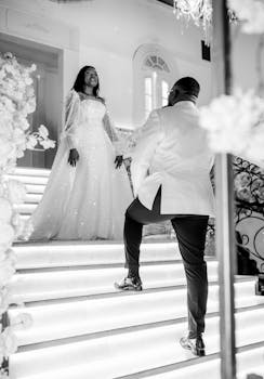 Elegant black and white photo of a bride and groom on a romantic staircase, capturing a timeless wedding moment.