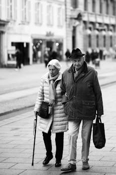 Senior couple walking arm in arm on a city street in black and white.