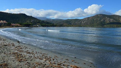 Free Serene view of Saint-Florent beach with mountains and clear skies in Corsica, France. Stock Photo