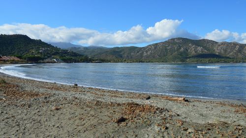 Free Beautiful scenic view of a serene beach in Saint-Florent, Corsica, France with mountains and blue sky. Stock Photo