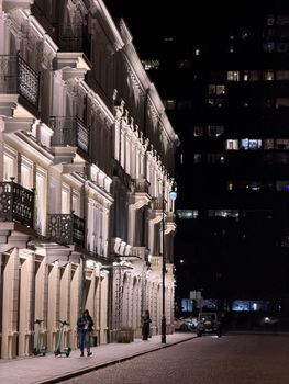 Charming street in Warsaw at night with classic architecture and streetlights.