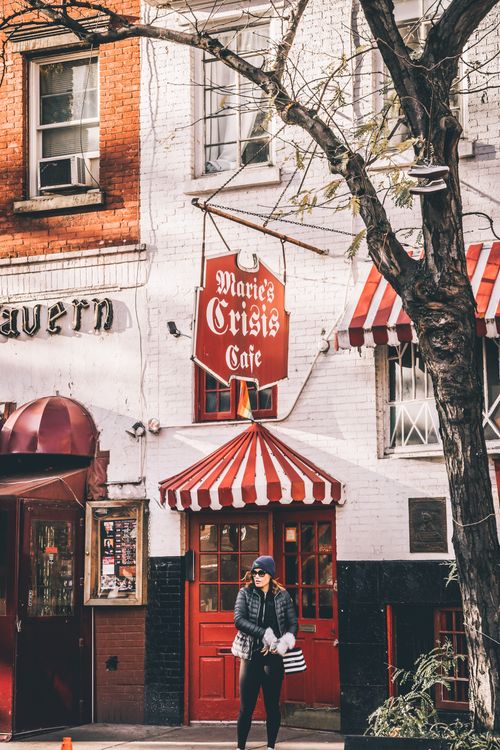 Free Candid street scene of a woman walking past Marie's Crisis Cafe in Greenwich Village, NYC. Stock Photo