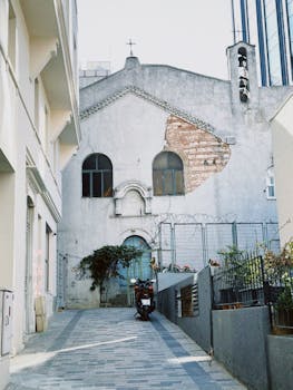 Old church facade with brick exposure in a narrow urban alleyway.