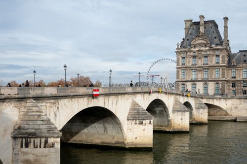 Free View of Pont du Carrousel and Louvre Museum in Paris with a Ferris wheel in the background. Stock Photo