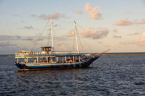 Free A traditional blue boat sails peacefully on the waters near Porto Seguro, Brazil during sunset. Stock Photo