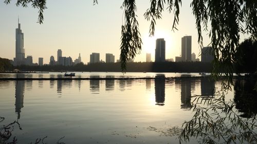 Free Cityscape with sunset reflections over water and silhouettes of skyscrapers. Stock Photo