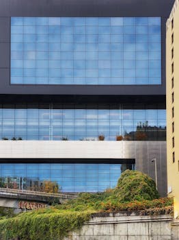 Contemporary architecture with glass facade and urban greenery in a city landscape.