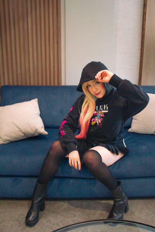 Free Young adult in stylish outfit sitting on a blue sofa indoors. Stock Photo