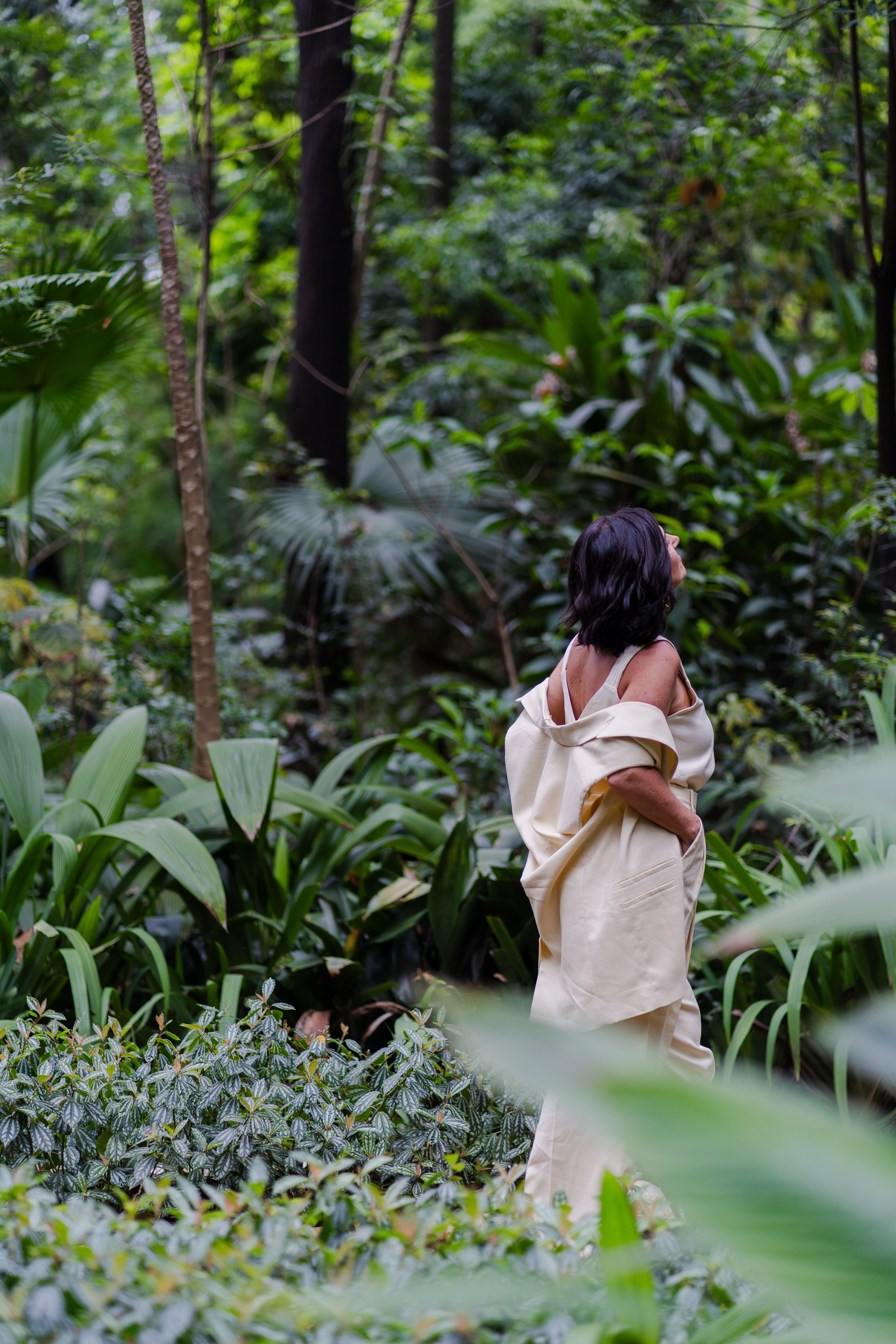 Woman in Beige Dress Walking through Lush Forest · Free Stock Photo