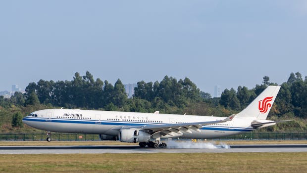 Air China Airbus A330-300 landing with smoke on runway, surrounded by greenery.