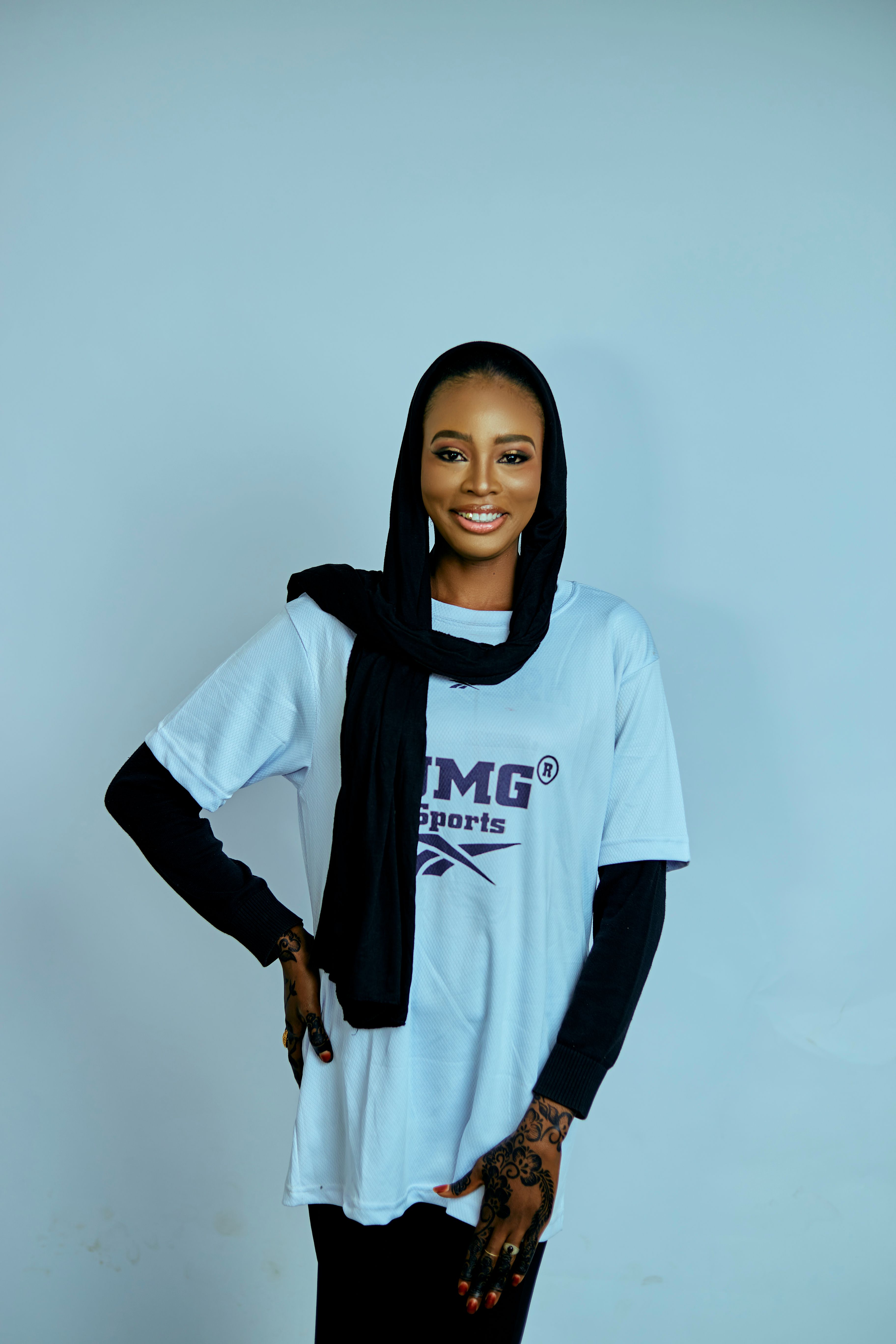 Confident woman in hijab wearing a TMG sports t-shirt, smiling.