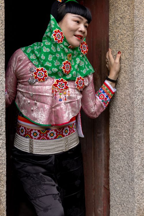 Free Woman in colorful traditional attire with floral patterns and jewelry, posing in a doorway. Stock Photo