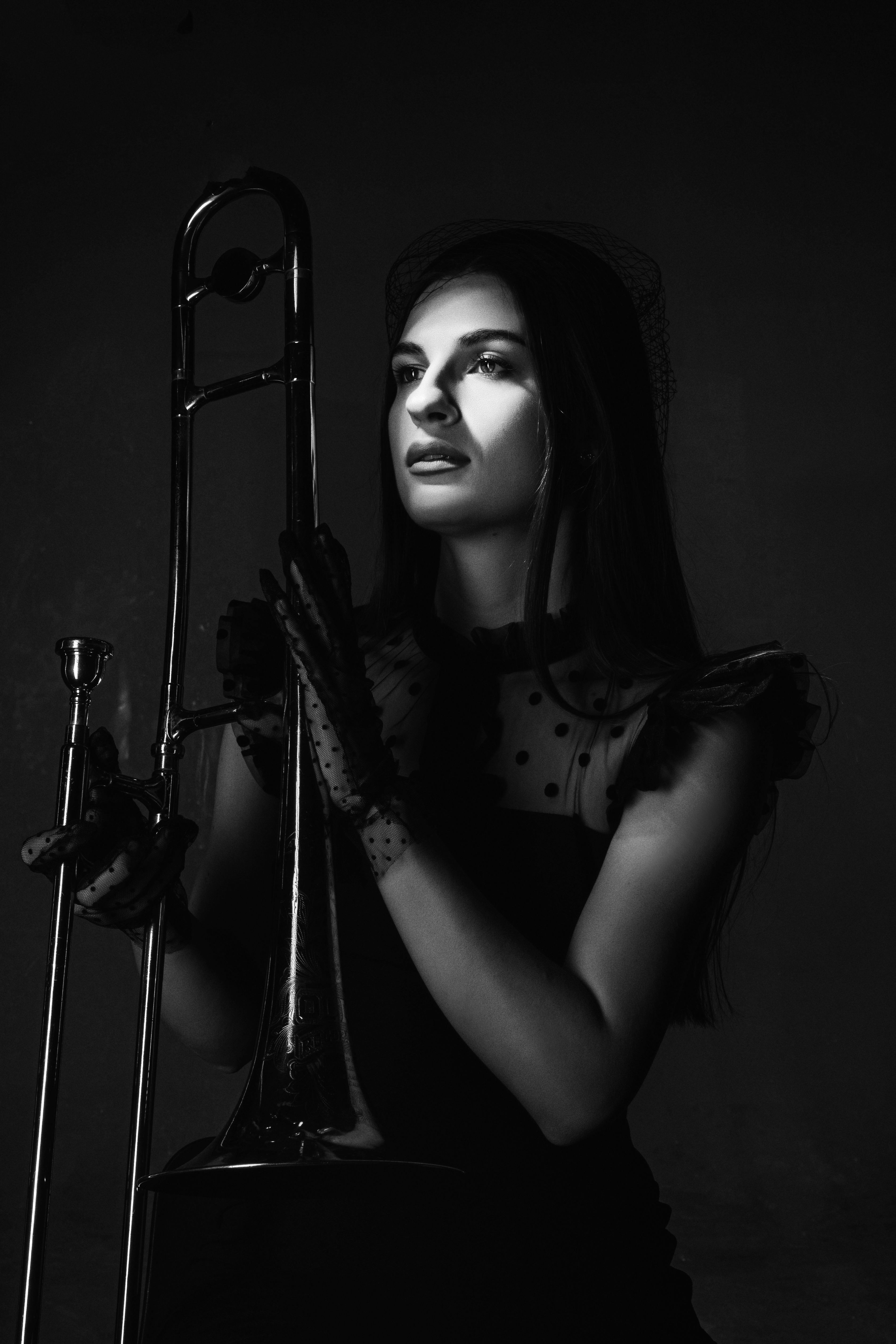 Black and white portrait of a woman holding a trombone, showcasing elegance and musical artistry.