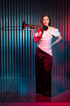 Stylish woman with trombone in artistic studio lighting against a metallic background.
