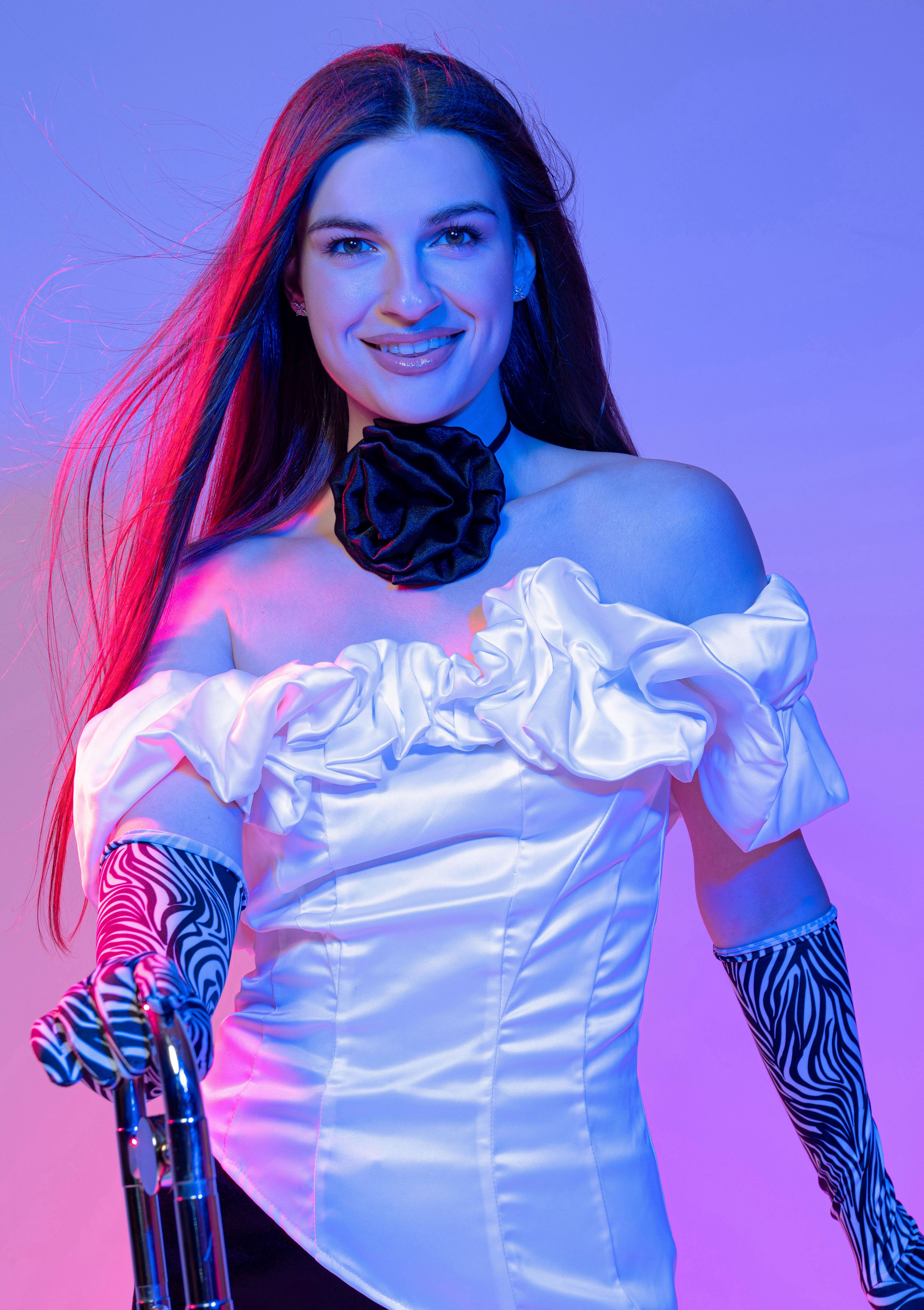 Elegant woman in white dress with zebra gloves, captured in bold red and blue lighting for a modern fashion look.