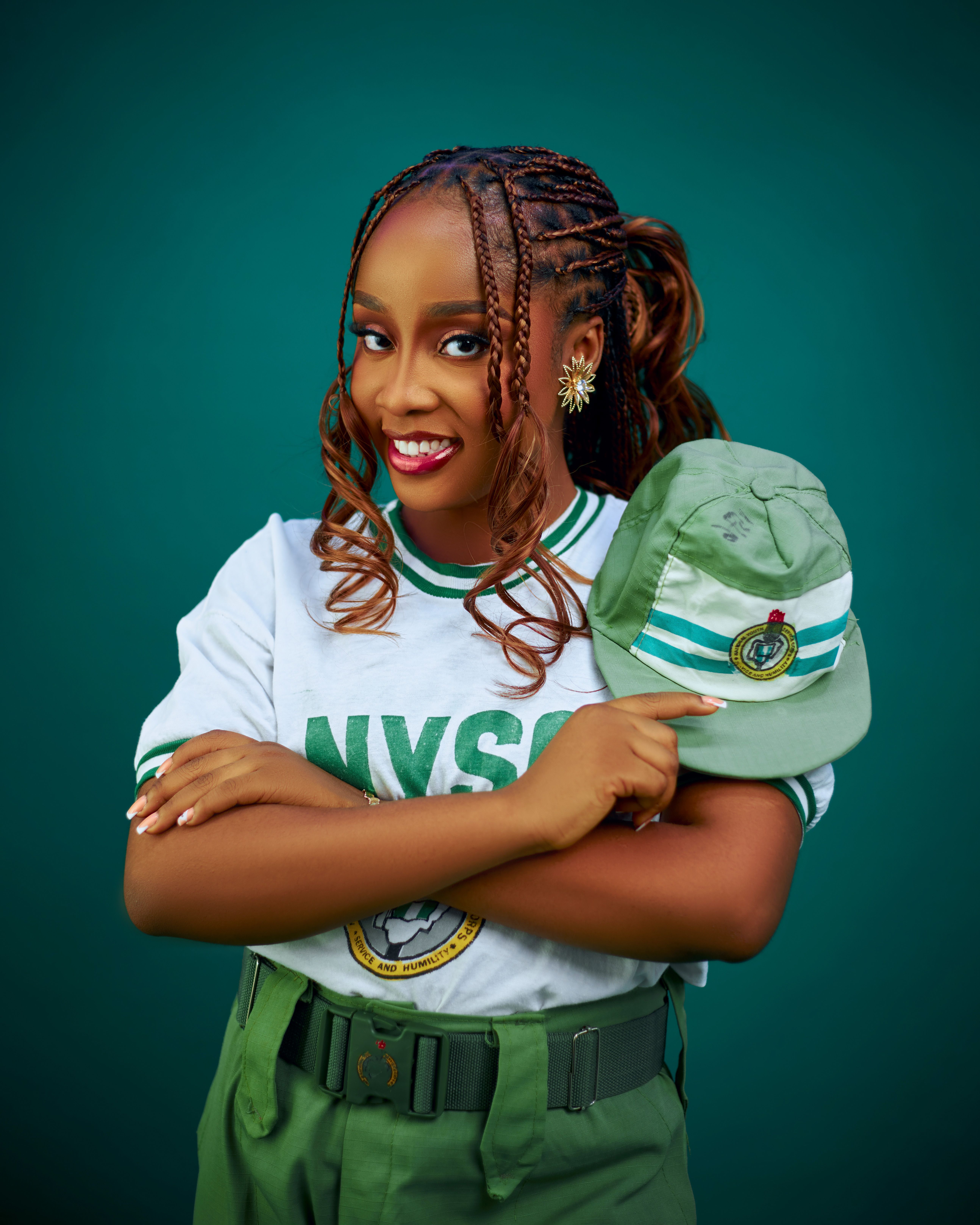 Smiling Woman in NYSC Uniform Holding Cap · Free Stock Photo