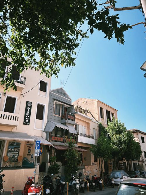 Free Picturesque European street lined with shops, trees, and parked motorcycles on a sunny day. Stock Photo
