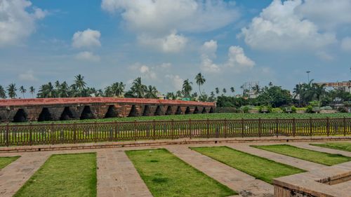 Free Ancient brick bridge surrounded by greenery and palm trees under a bright blue sky. Stock Photo