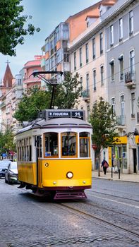 Charming Lisbon street with classic yellow tram and historic architecture on a sunny day.