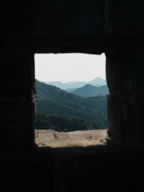 Free View of mountain landscape through a window in an ancient wall. Stock Photo