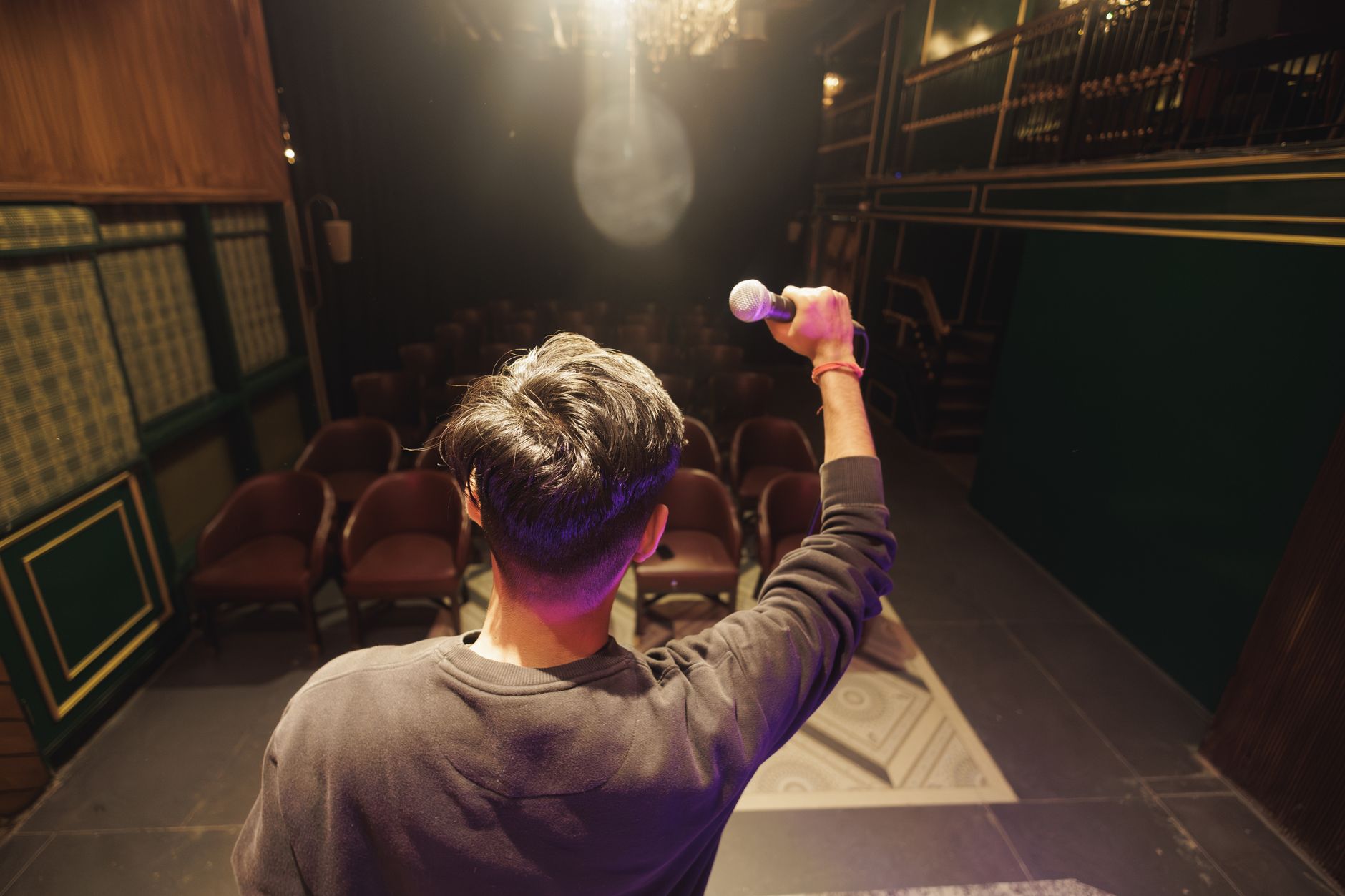 A performer holding a microphone on stage, preparing for a poetry performance