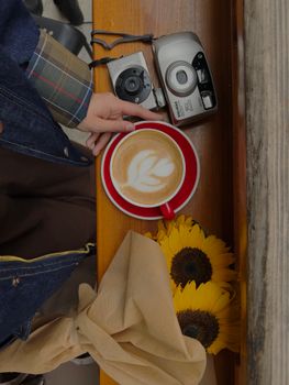 Flat lay of coffee, vintage cameras, and sunflowers for a cozy autumn vibe.