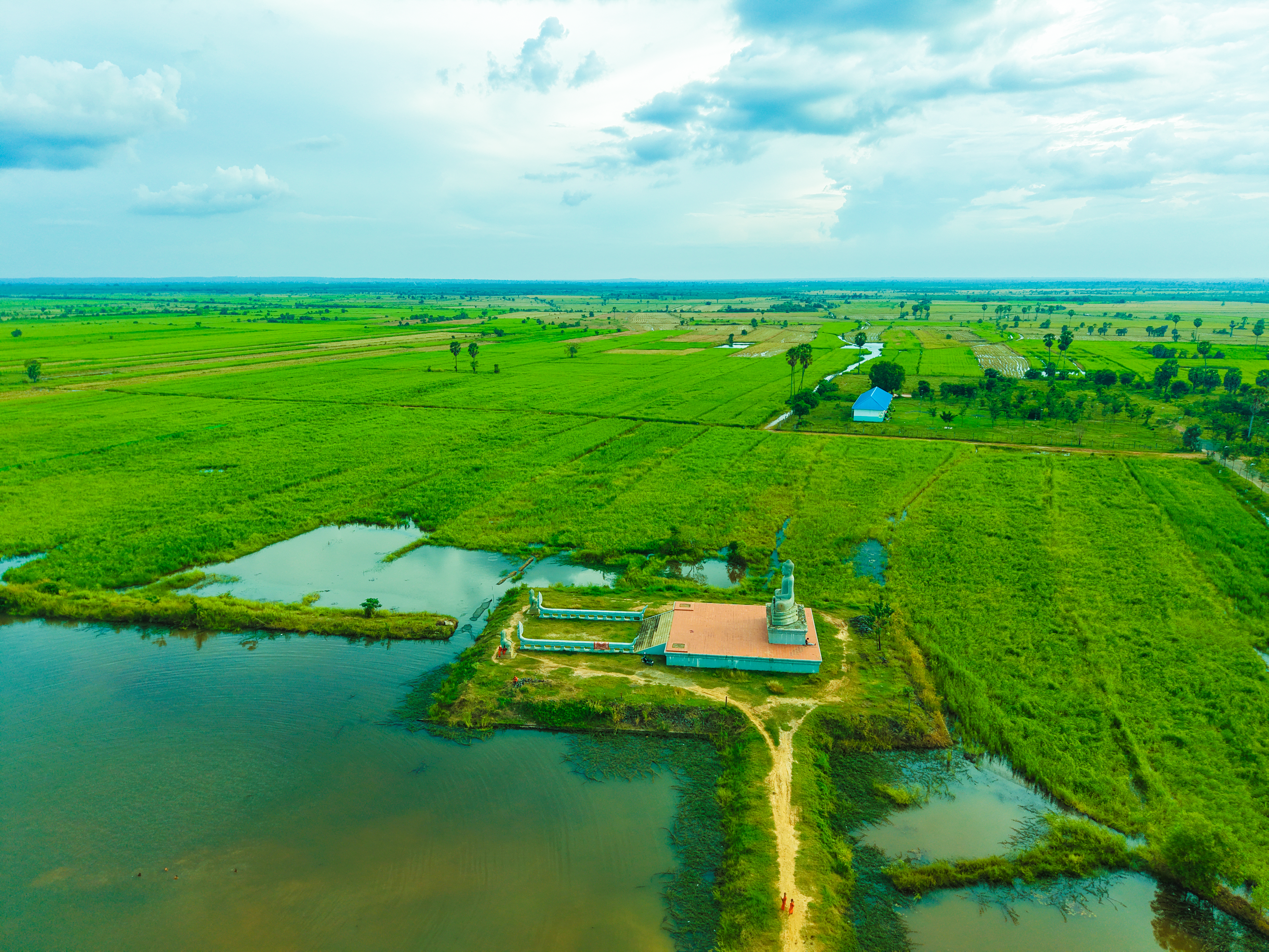 A breathtaking aerial view of Cambodia's lush countryside with a traditional temple by a water body.