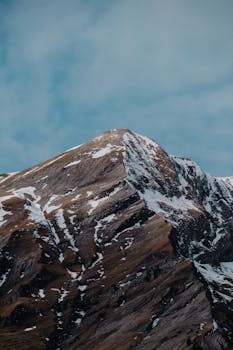 Breathtaking view of a snow-covered mountain peak reaching into a clear blue sky, perfect for nature enthusiasts.