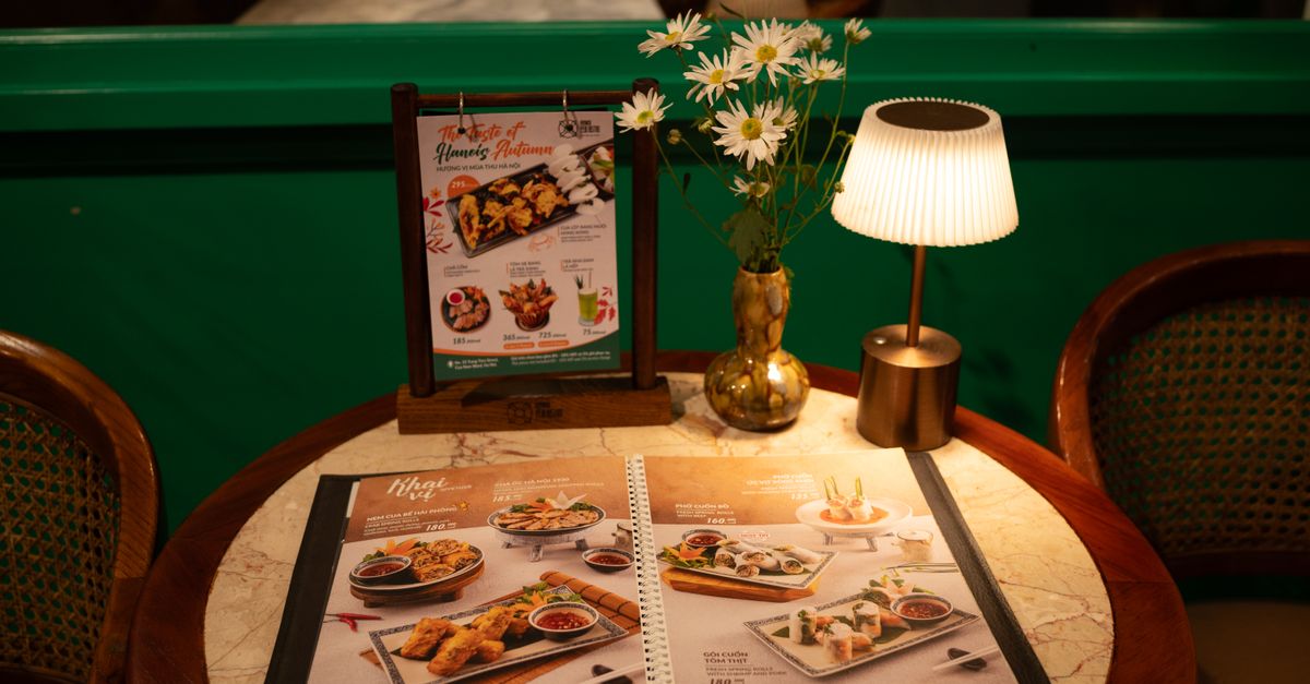 Warm ambiance at restaurant table with menu, flowers, and soft lighting.