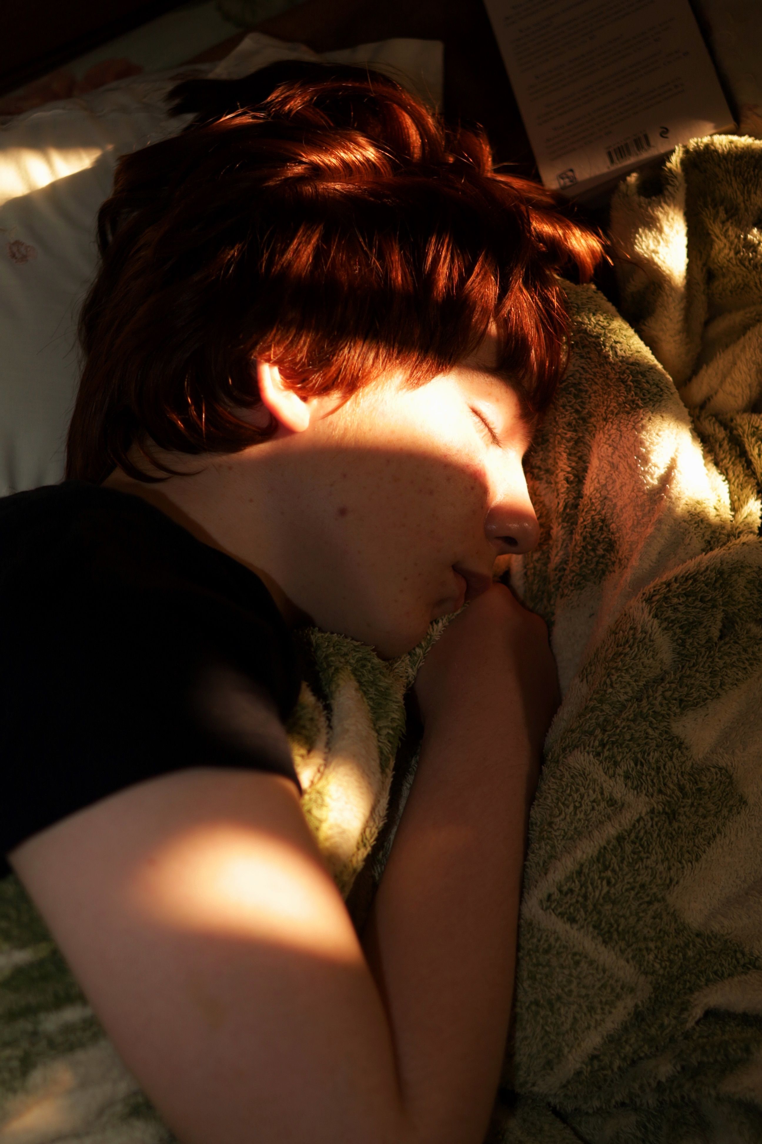 A young adult peacefully sleeping with sunlight casting gentle shadows.