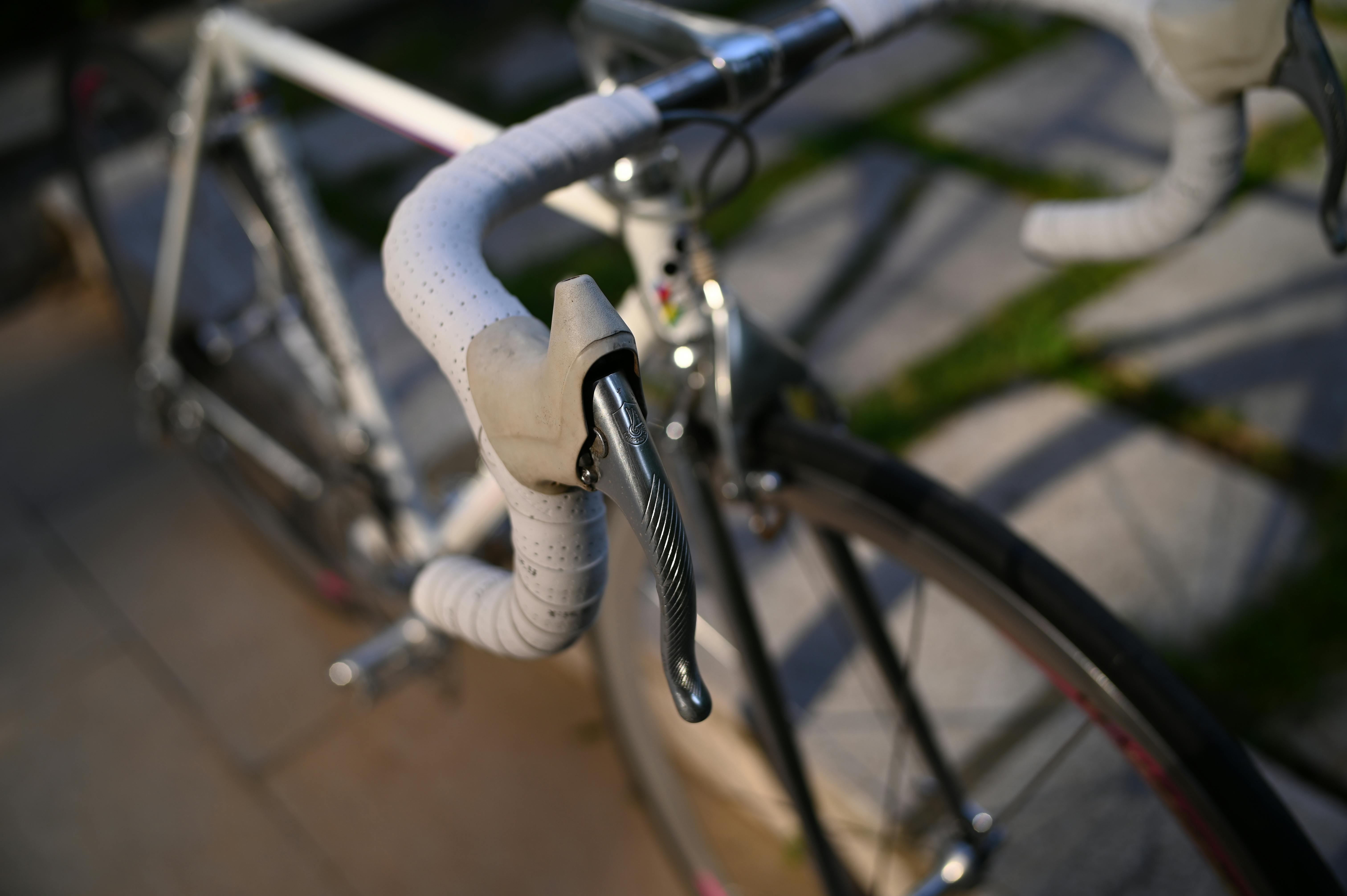 Detailed focus on a road bike's handlebars with sunlight highlighting the textures.