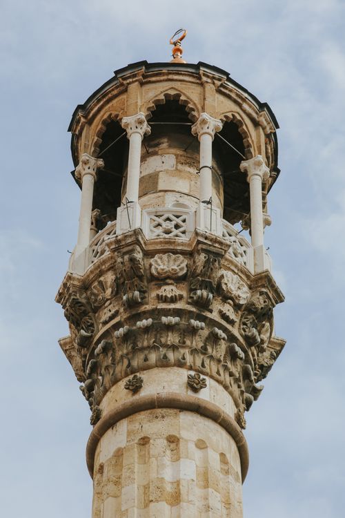 Free Close-up view of an intricately designed architectural tower with stone carvings against a blue sky. Stock Photo