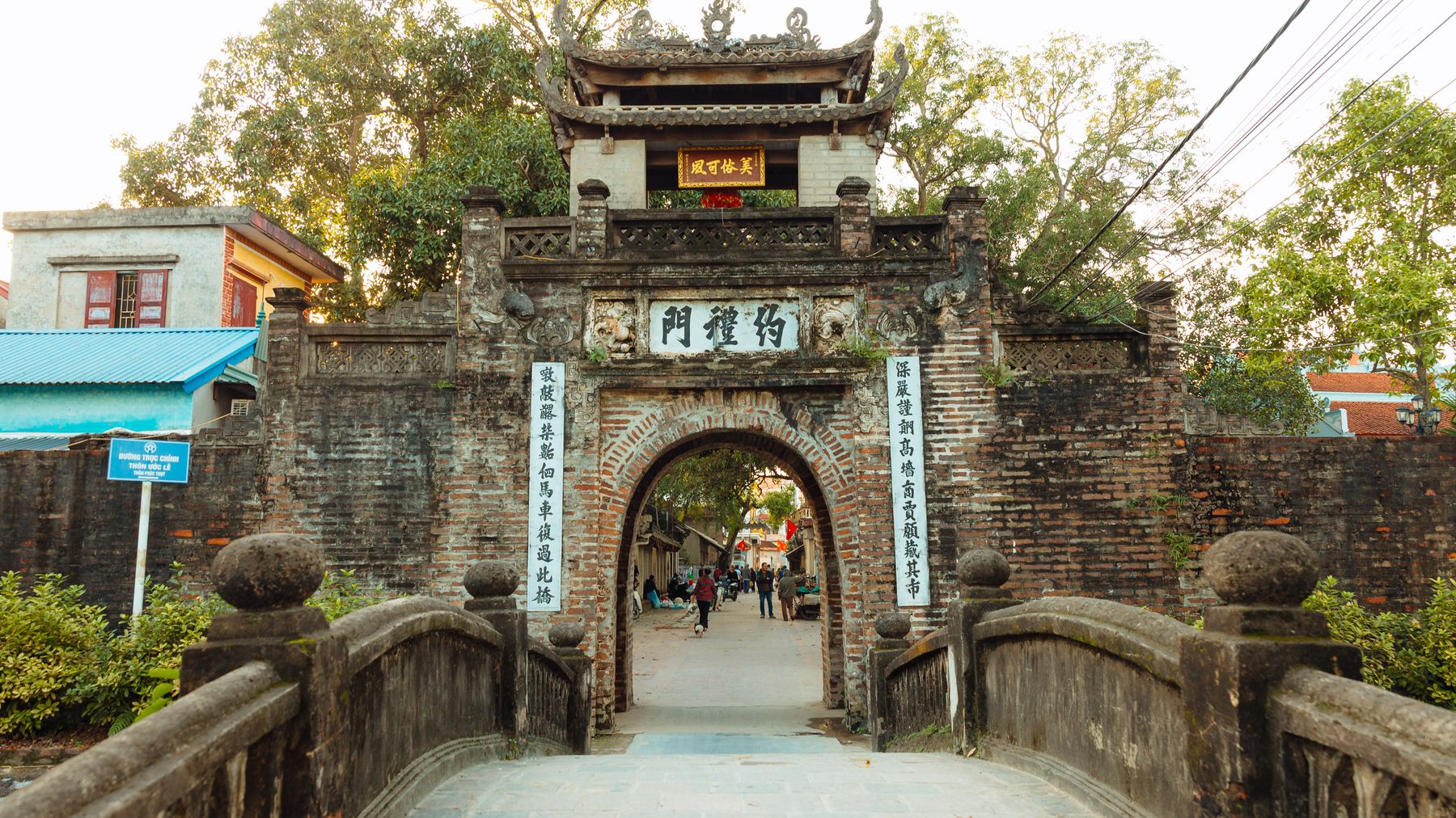 Traditional stone gate entrance in a historic Vietnamese village during the day.