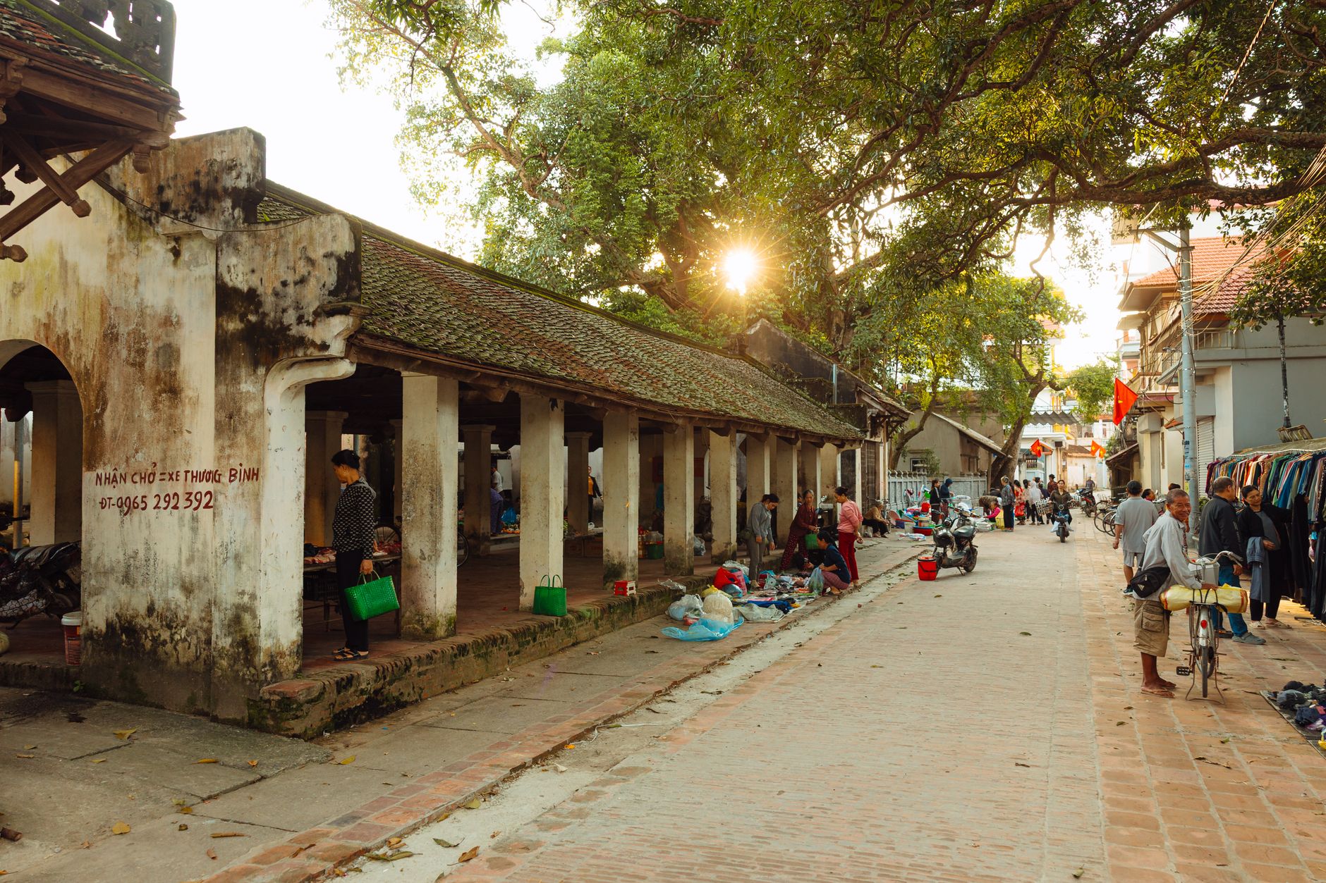 A serene village market scene with people and vintage architecture at sunset.