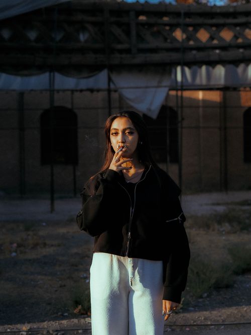 Free A moody portrait of a woman smoking in a casual setting, creating a dramatic and contemplative mood. Stock Photo