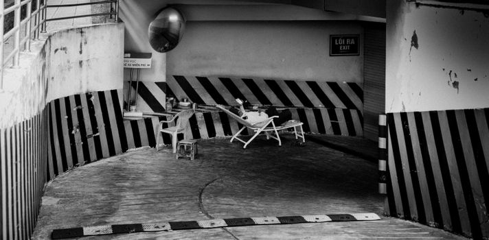 Monochrome image of an urban alley with a resting area, emphasizing solitude.