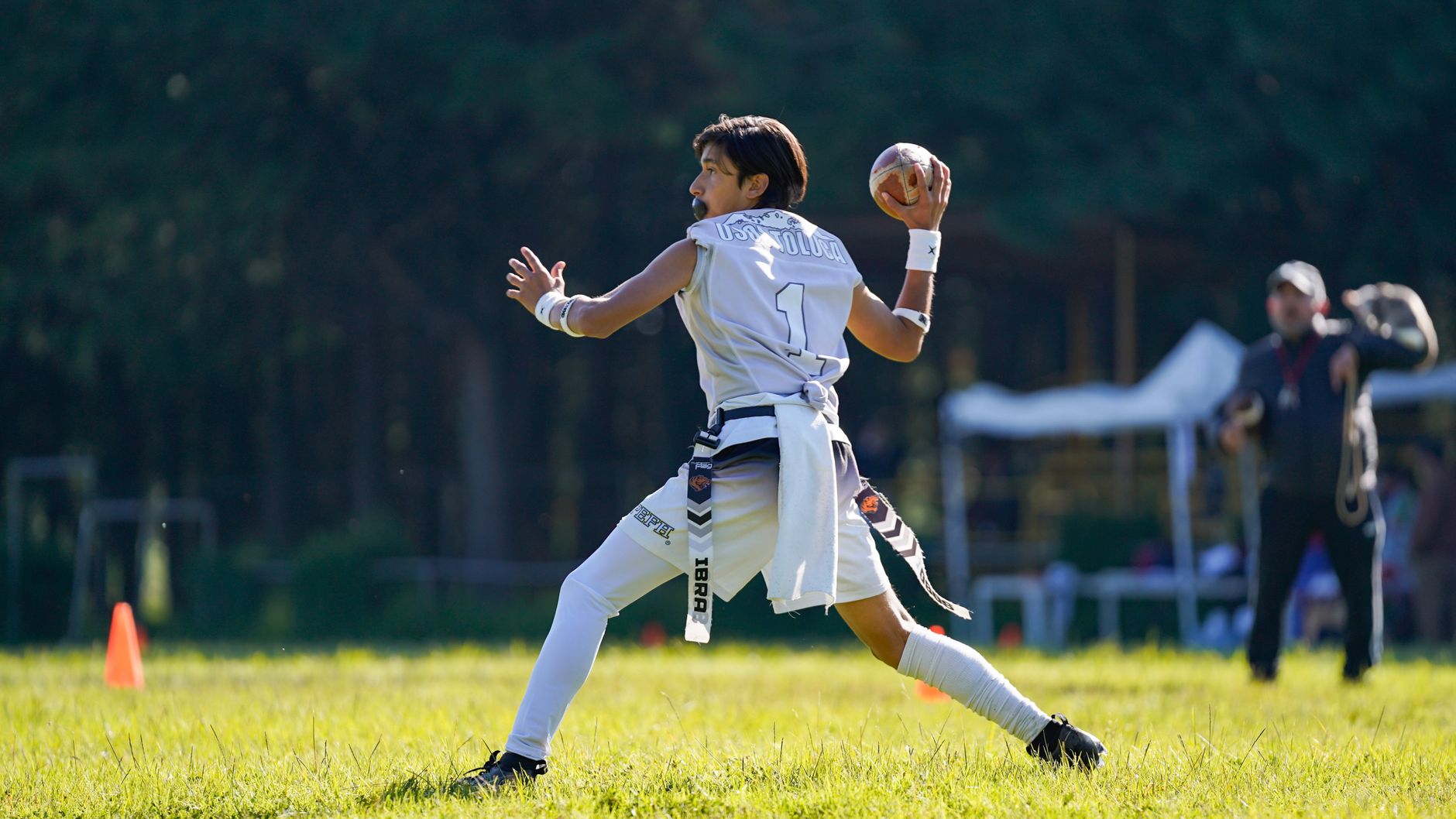 Young athlete in motion during flag football game outdoors.