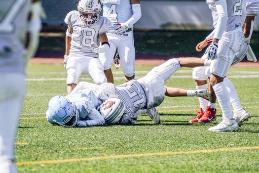Dynamic action scene of a youth American football game with players in full gear.