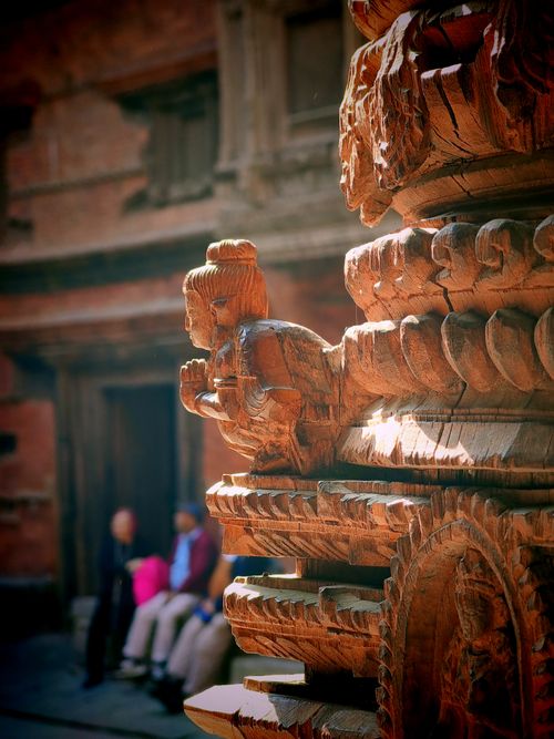 Free Beautifully detailed wooden carving with blurred background in a historic courtyard setting. Stock Photo