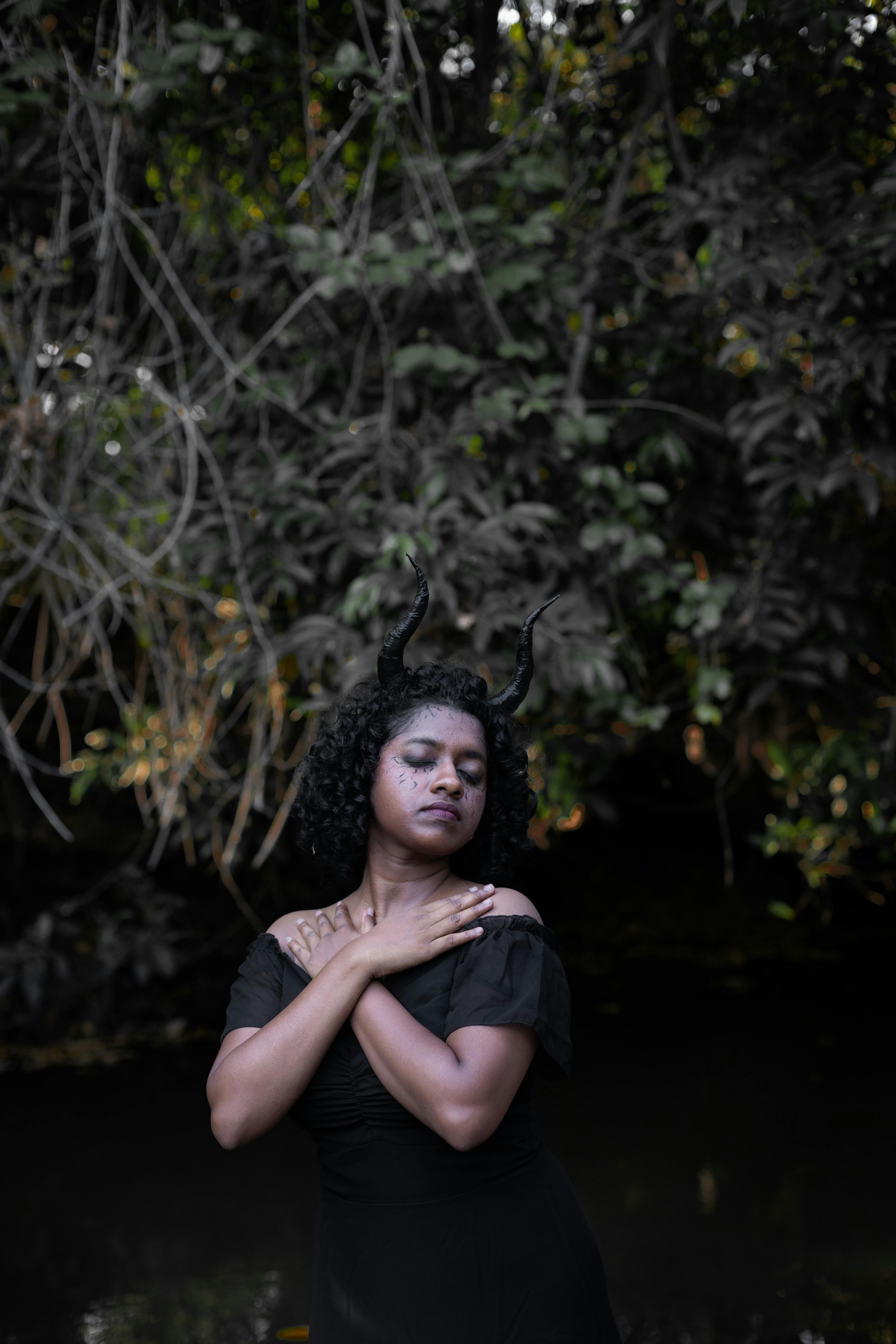 Gratuit Une femme aux cornes recourbées pose de manière éthérée dans un décor de forêt sombre et gothique. Photos