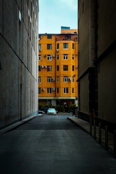 A vibrant yellow apartment building seen through a narrow alley, highlighting urban architecture in Yerevan, Armenia.