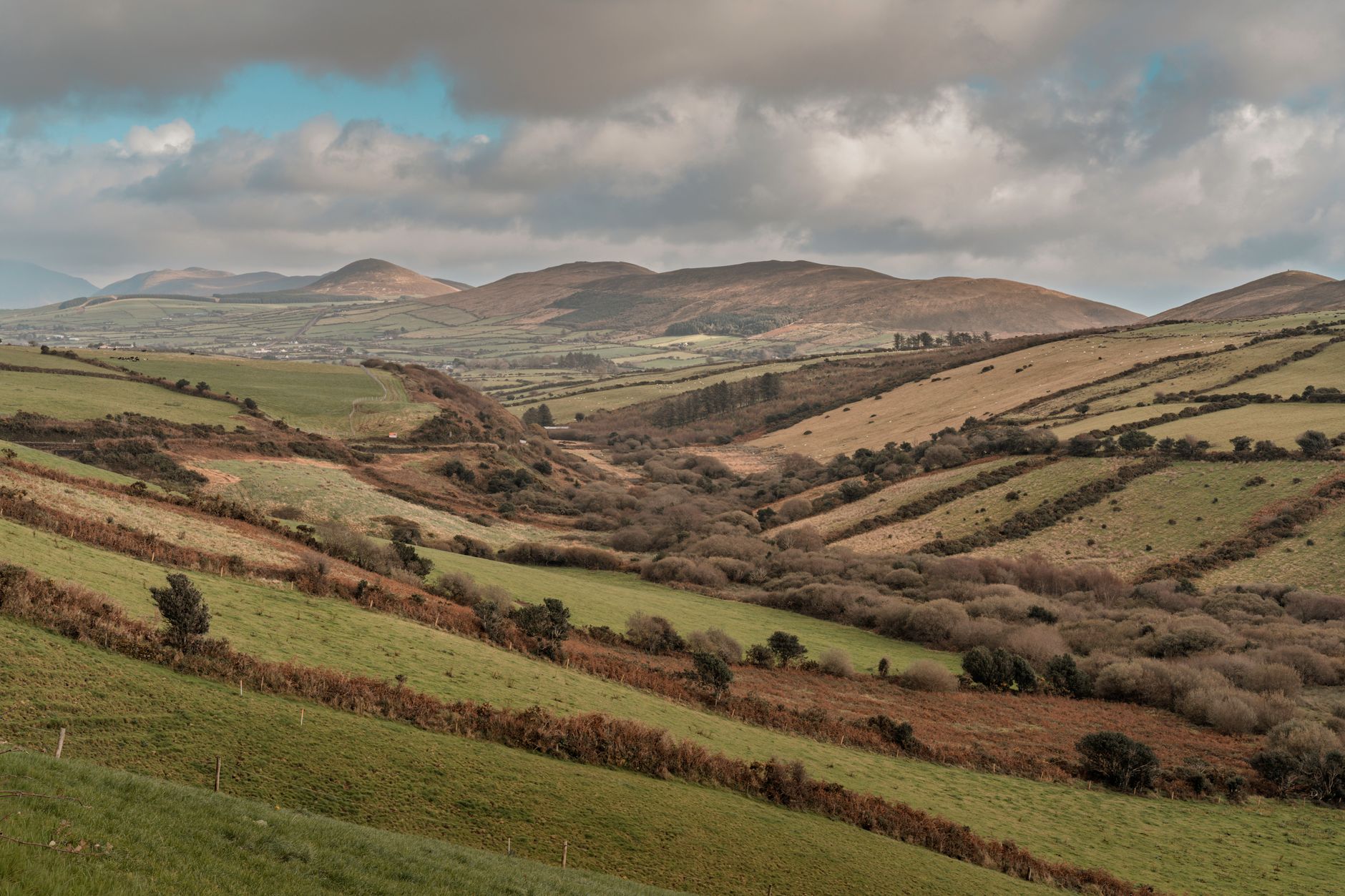 Explore the serene beauty of Ireland's rolling hills and lush landscapes under a cloudy sky.