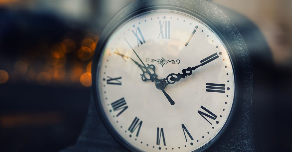Close-up of a vintage clock with Roman numerals, softly lit background.