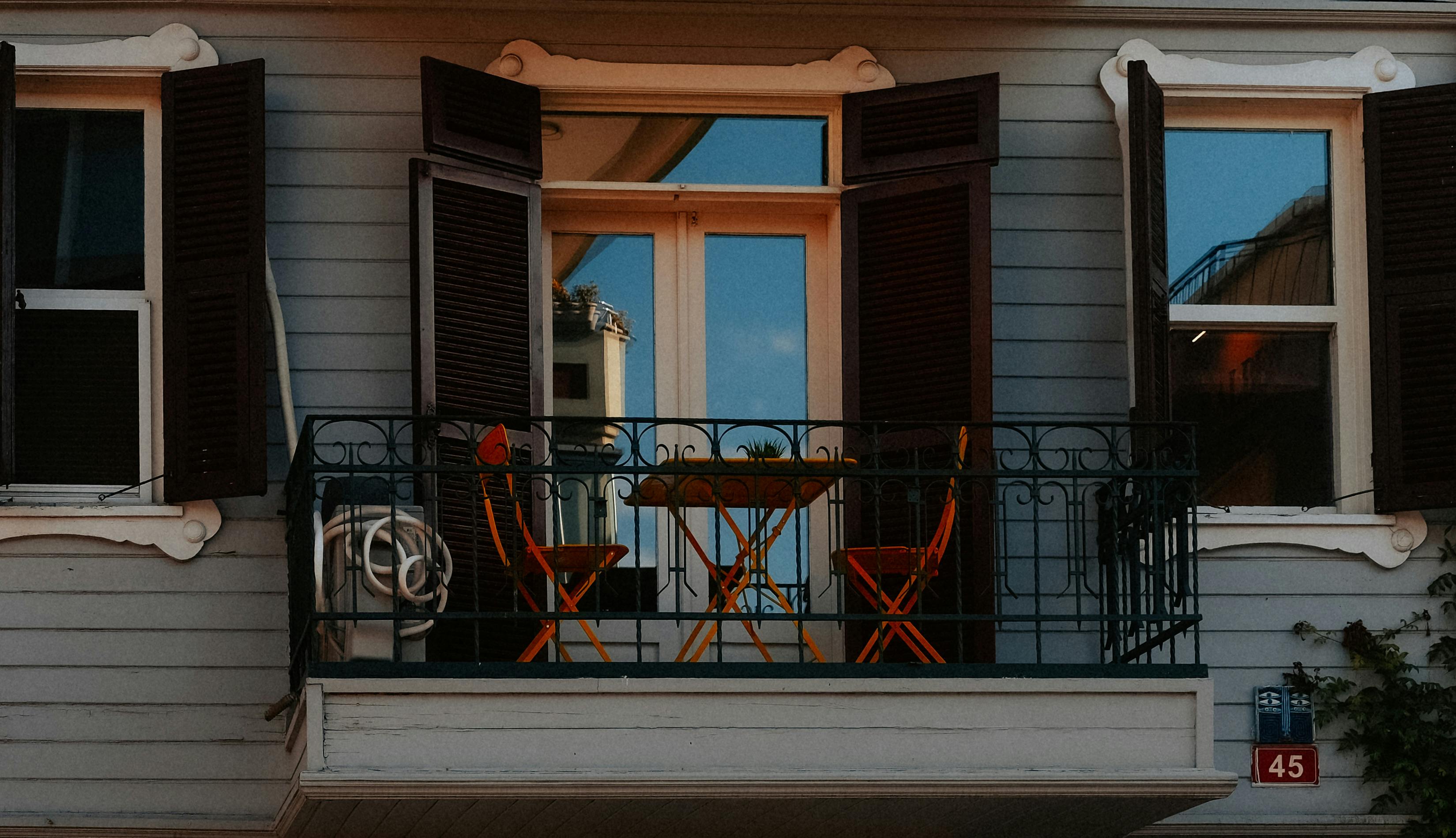 Gratuit Balcon fermecător cu scaune portocalii, masă și ferestre deschise într-o zi însorită. Fotografie de stoc